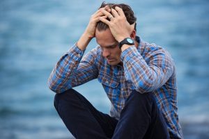 a mid age man crowched grasping head looking stressed