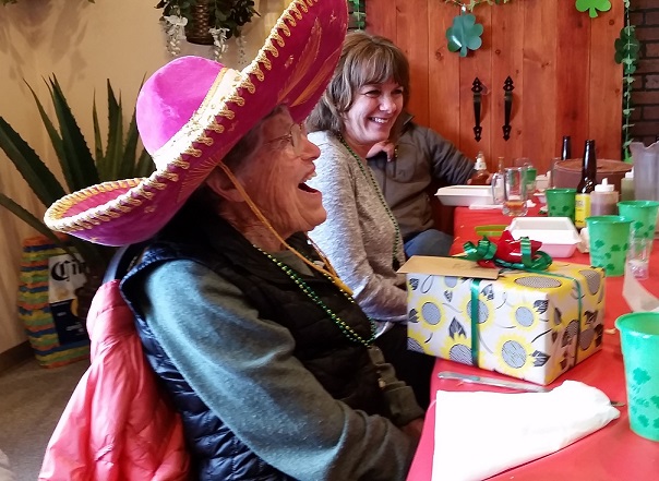 Elderly woman laughing and opening a gift.
