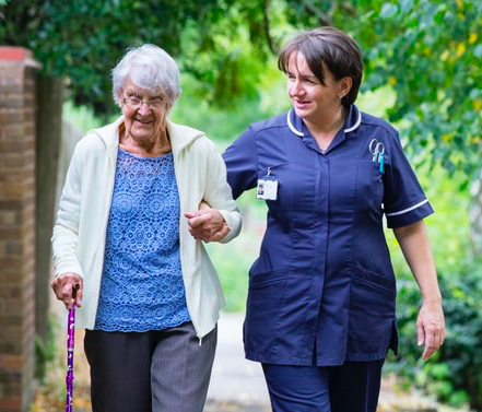 Caregiver walks with older woman.