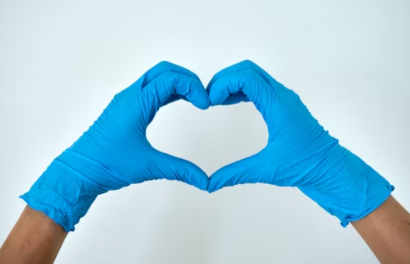 hands wearing blue medical gloves in the shape of a heart