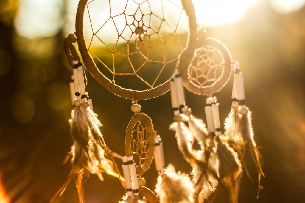 a dream catcher with the sun shining behind it